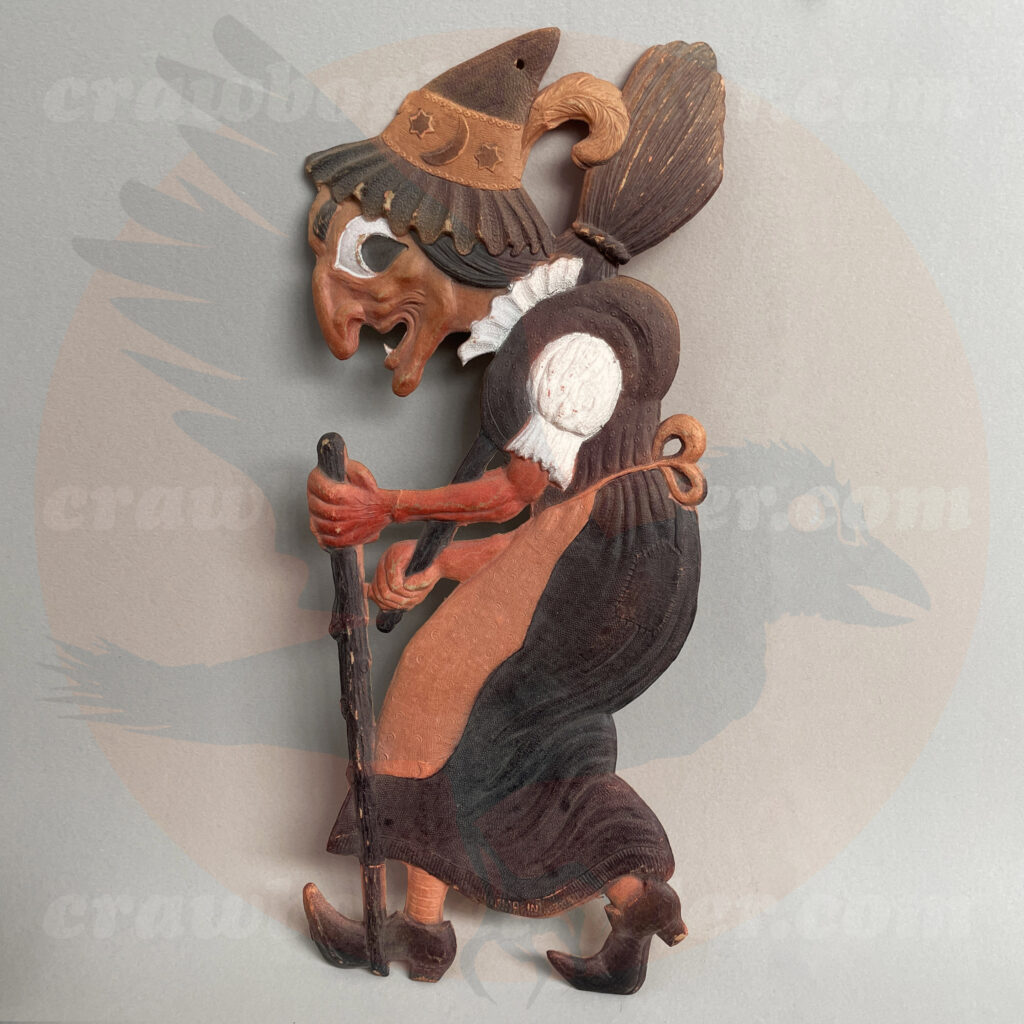 Walking witch with wooden cane and broom, with hat and feather, a German import pressed board vintage Halloween collectible offered by Craw-Bogle Trader trade-buy-sell online website collection, a companion site to The Halloween Retrospect archive library.